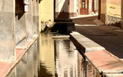 El lavadero tradicional de Pratdip, bañado por la luz, con las fachadas del pueblo reflejadas en el agua