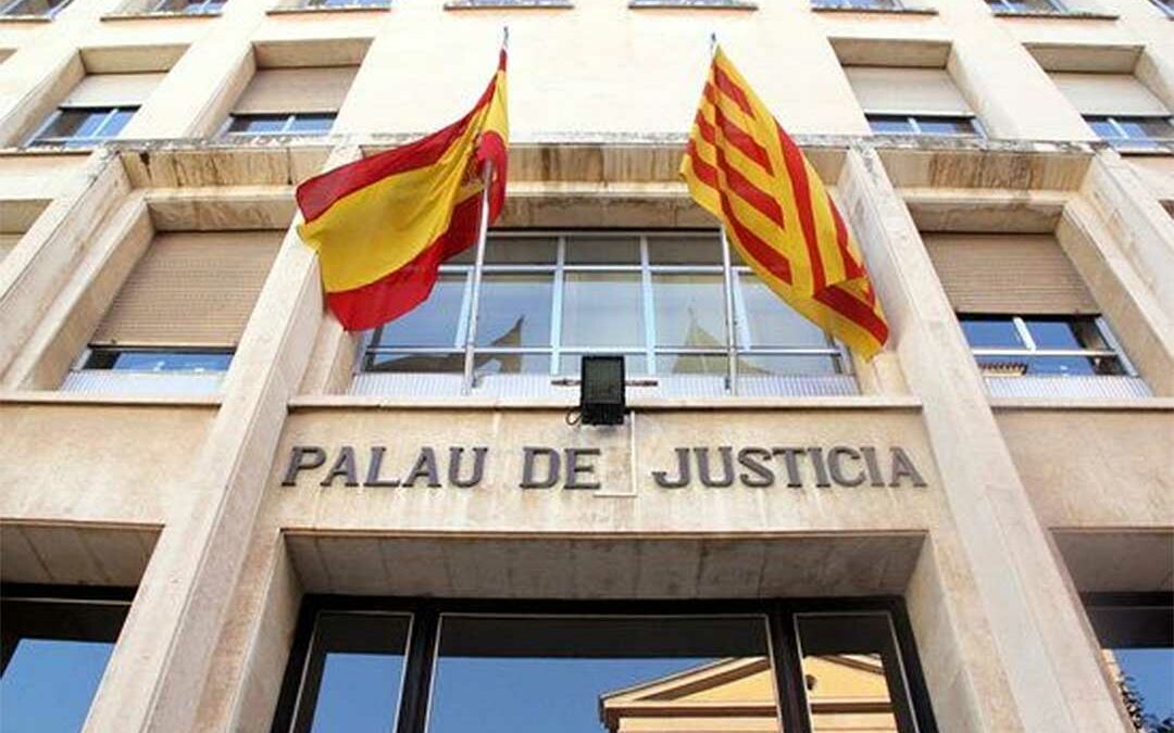 Fachada de un palacio de justicia con las banderas española y catalana.